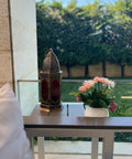 Decorative lantern and flowers on a table with a garden view