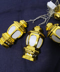 Gold lantern-shaped string lights on a dark blue fabric background