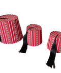 Three red and patterned hats with black tassels on a white background