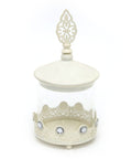 A glass jarr with metal id and with stons design in white color on white background.