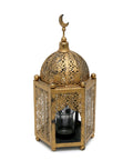 A vintage looking gold-colored metal lantern in the shape of a mosque with a glass cup for a candle, featuring intricate carvings and a crescent moon on top.