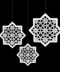Three white geometric star-shaped cutout decorations on a black background